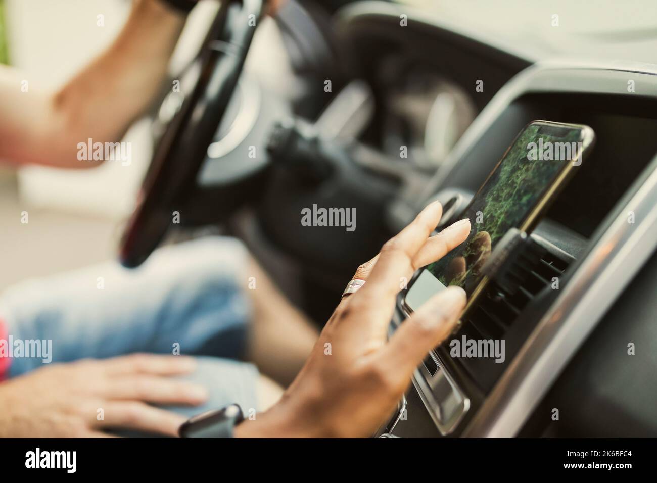 Mano di donna che utilizza il GPS tramite smartphone collegato al cruscotto in auto Foto Stock