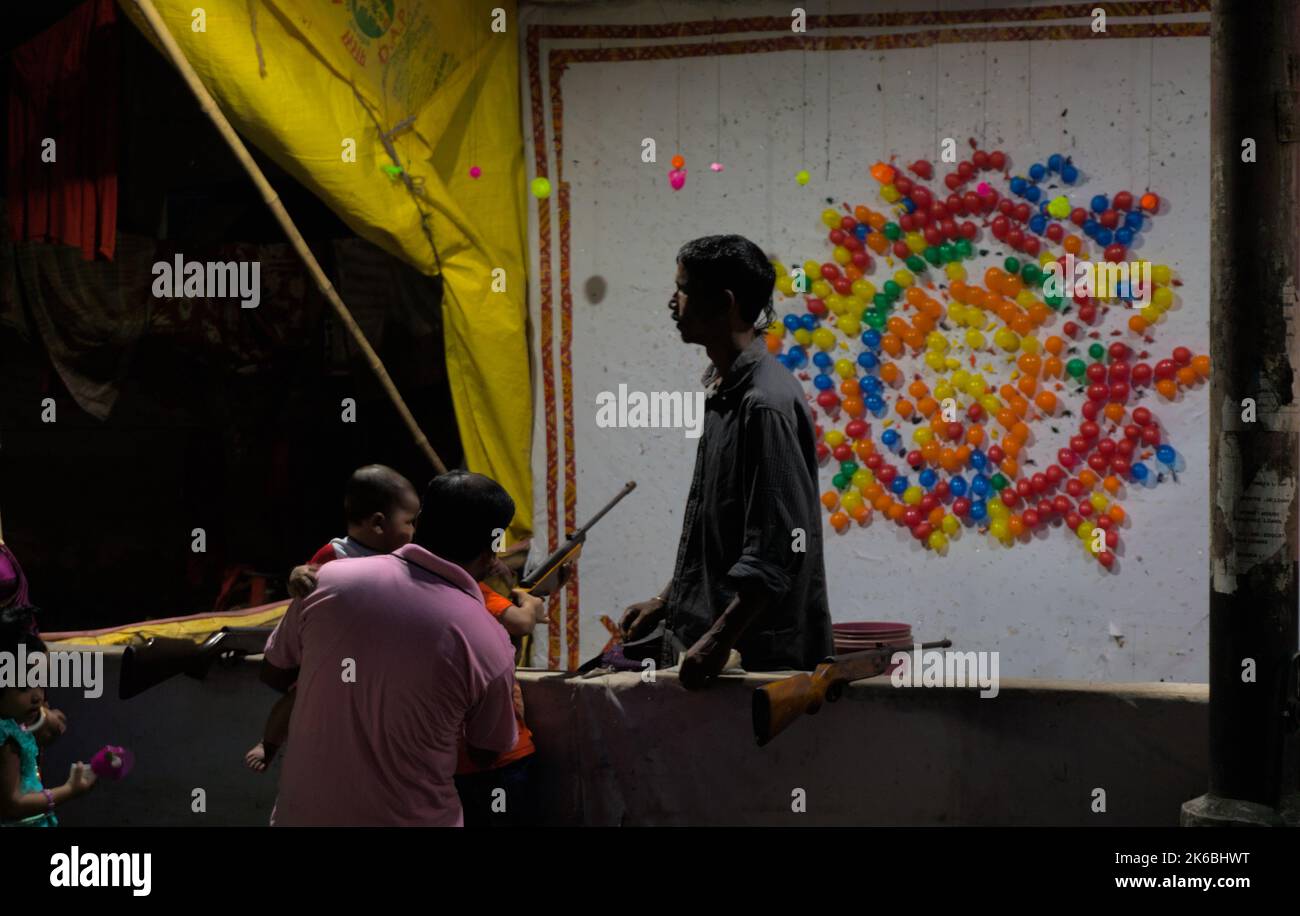 L'uomo insegna a suo figlio tiro bersaglio con la pistola ad aria in palloncino tiro stalla Foto Stock