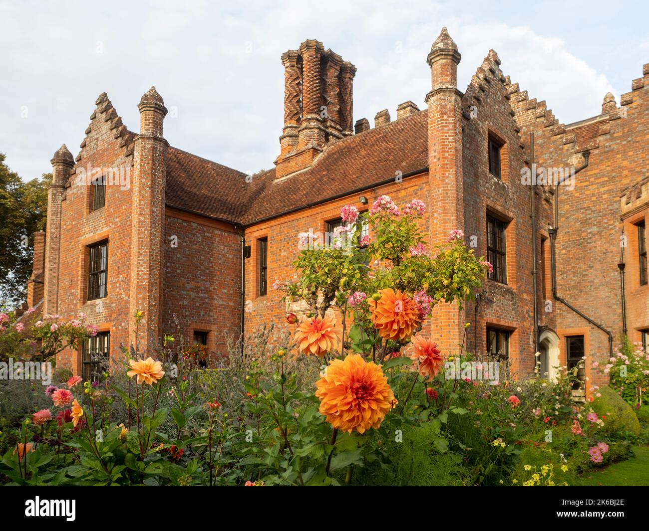 Chenies Manor e giardino circondato da colorate dahlias nel mese di ottobre.Dahlia 'Grande Ercole' fiori di bronzo arancione sopra il resto e Rosa 'Ballerinaa'. Foto Stock