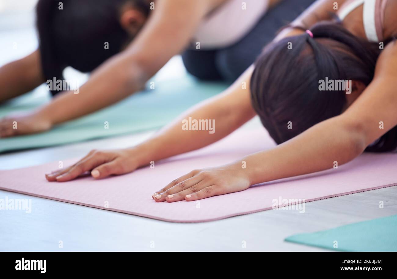 Rallentare e concentrarsi sulla consapevolezza. Primo piano di un gruppo di giovani donne sportive che fanno la posa dei bambini mentre si esercitano in uno studio di yoga. Foto Stock