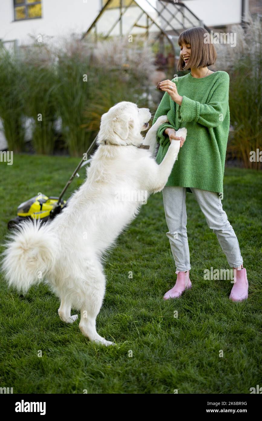 La donna gioca con il suo cane sul cortile mentre fa giardinaggio Foto Stock
