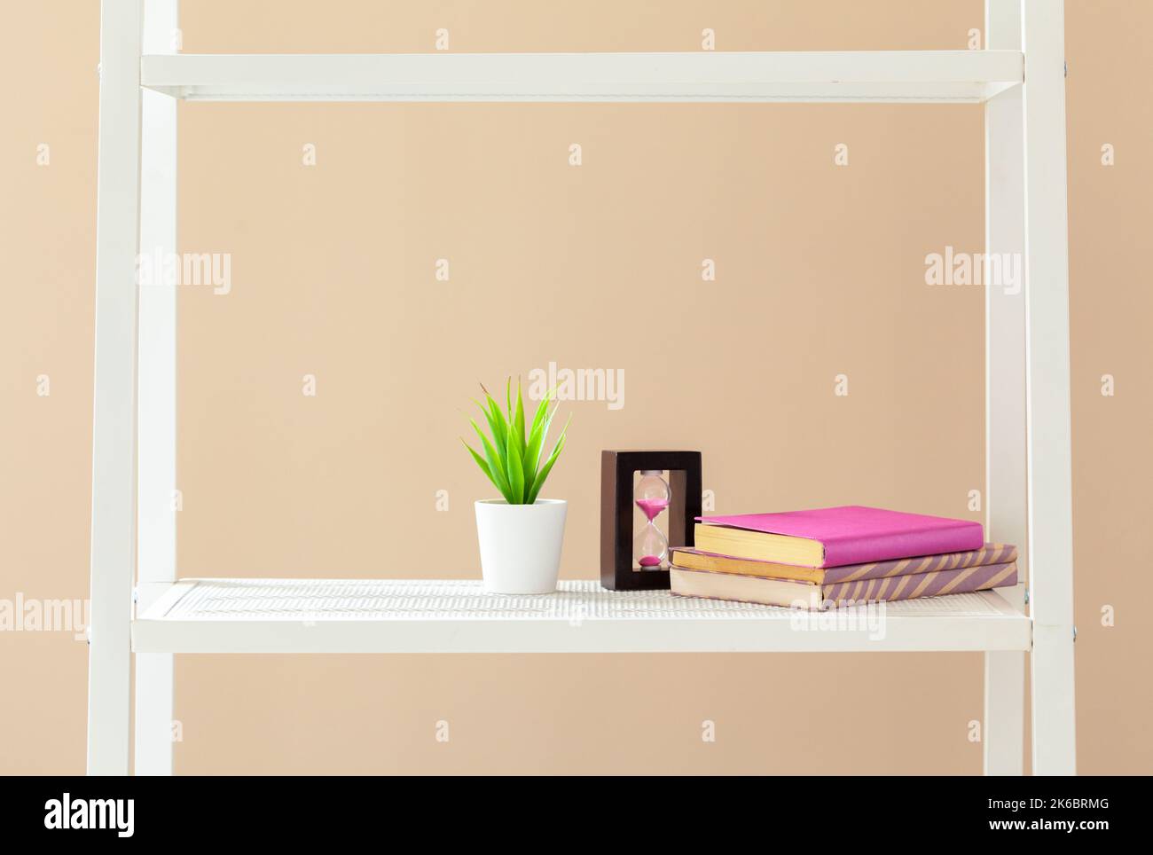 Scaffale bianco con libri e cancelleria contro il muro beige Foto Stock