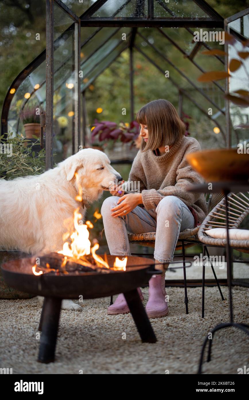 Donna con cane vicino al fuoco in giardino Foto Stock