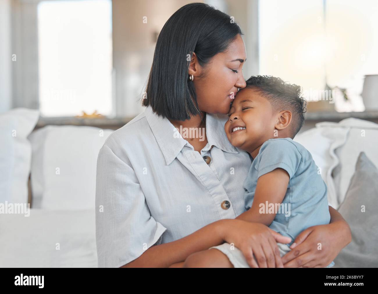 Niente di più confortante di un abbraccio di mamma, una giovane donna affettuosa con suo figlio sul divano. Foto Stock