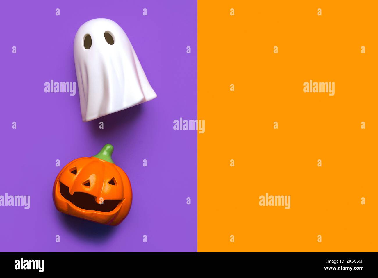Sfondo concetto di Halloween. Divertente zucca di Halloween e fantasma di Halloween con spazio di copia su sfondo viola e arancione Foto Stock