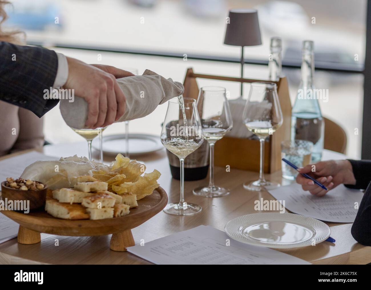 Sommelier che versa vino bianco in bicchieri con bottiglia nascosta Foto Stock