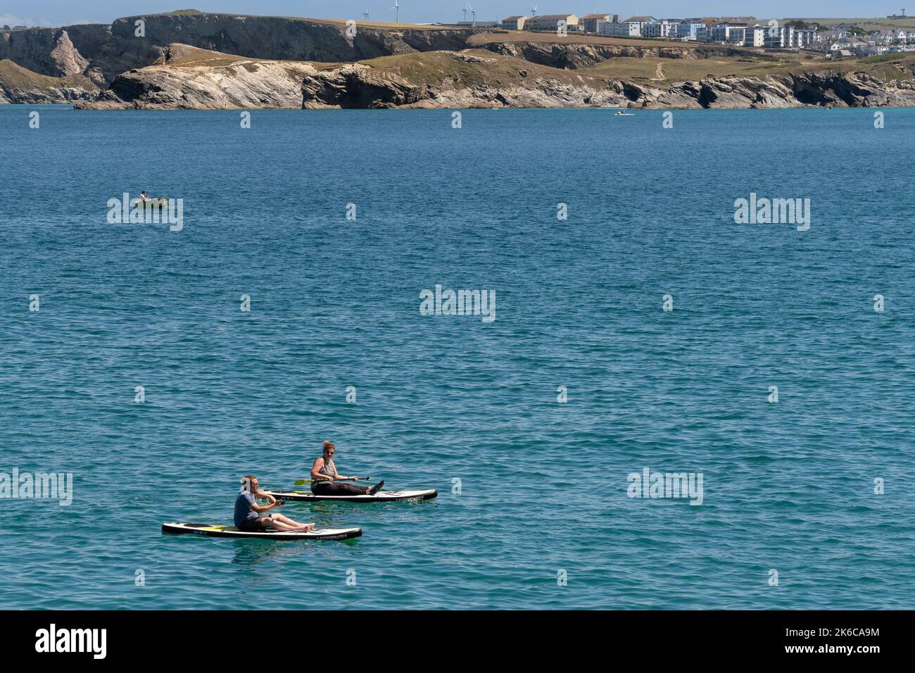 Due vacanzieri seduti su stand Up Paddleboards a Newquay Bay in Cornovaglia in Inghilterra nel Regno Unito. Foto Stock