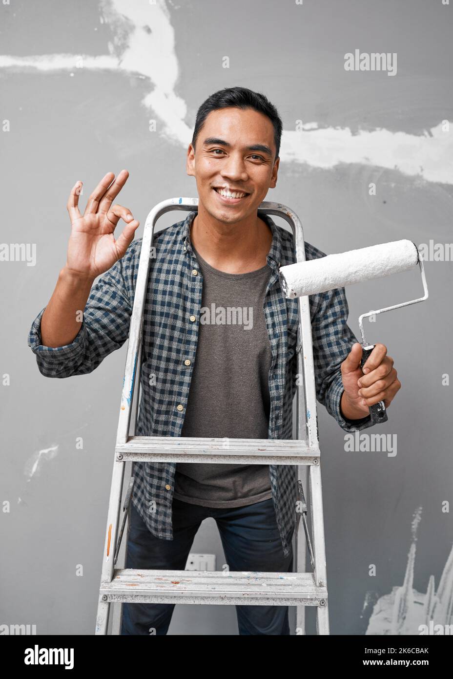 Un uomo asiatico attraente mostra un gesto mano OK mentre si prepara a dipingere Foto Stock