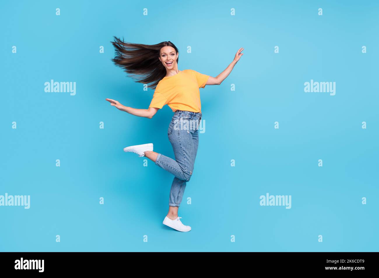 Foto a tutta lunghezza di bella donna lucido indossare t-shirt giallo avere divertimento spazio vuoto isolato sfondo di colore blu Foto Stock