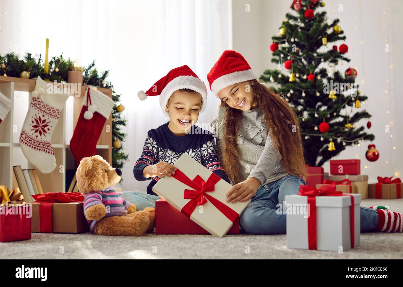 Felice fratello e sorella trovare un regalo magico mentre aprire i regali di Natale insieme Foto Stock