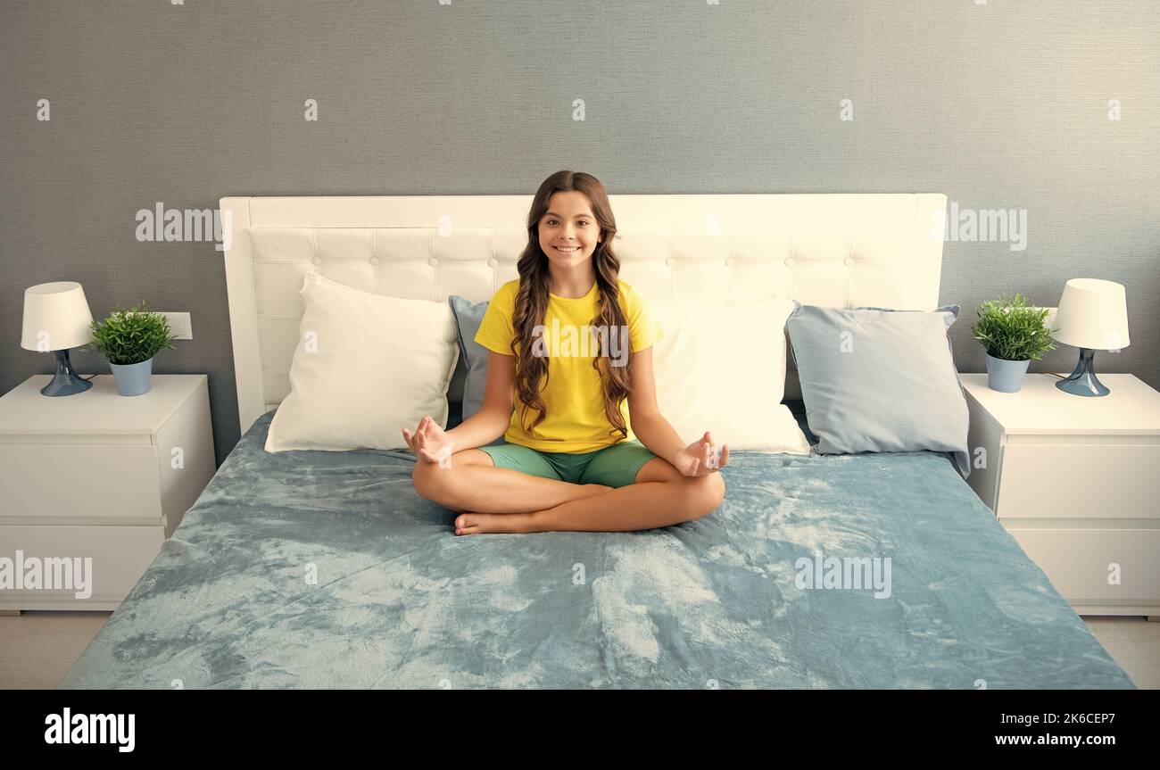 Bambino adolescente che pratica la meditazione in camera da letto. Meditazione mattutina a letto. Foto Stock