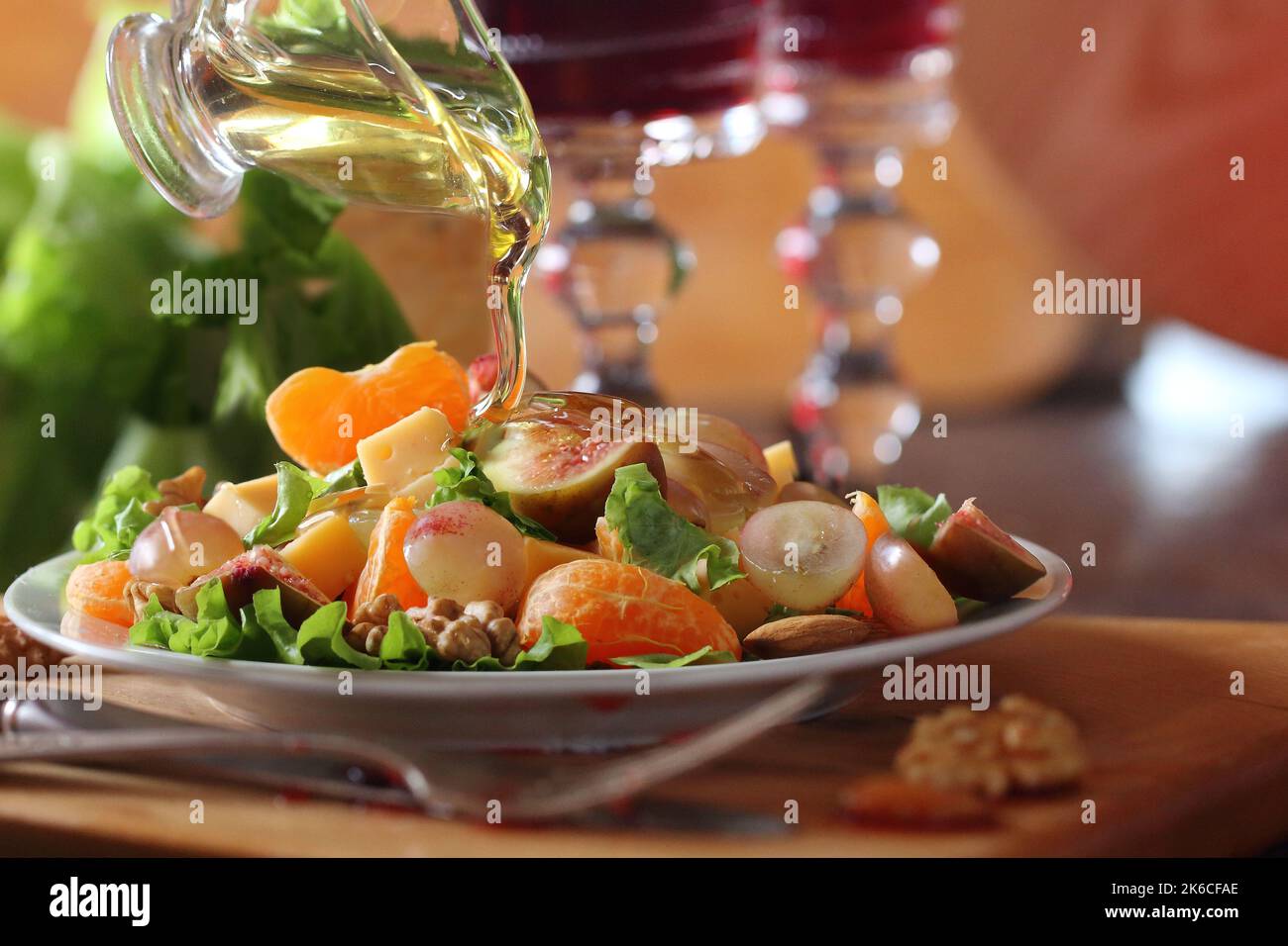 La mano della donna che versa miele sopra frutta e insalata di formaggio Foto Stock