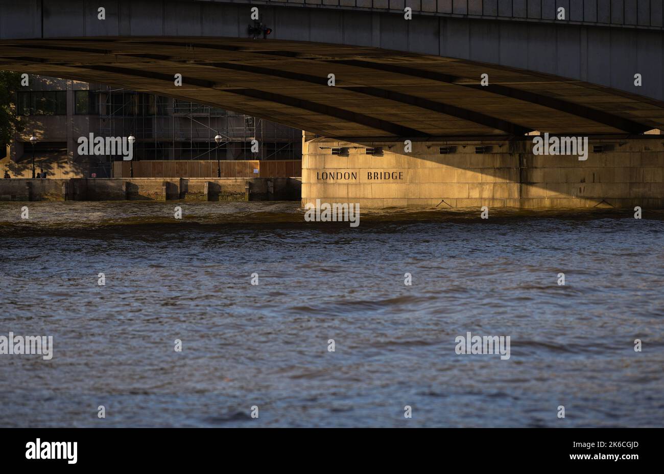 Il London Bridge cattura la luce della sera che evidenzia il nome sulla colonna sotto il ponte. Foto Stock