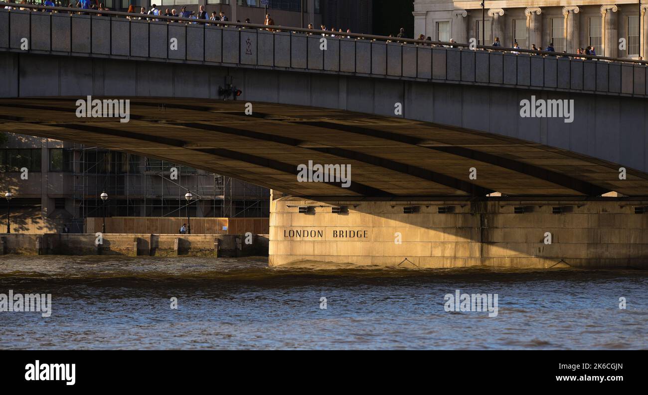 Il London Bridge cattura la luce della sera che evidenzia il nome sulla colonna sotto il ponte. Foto Stock