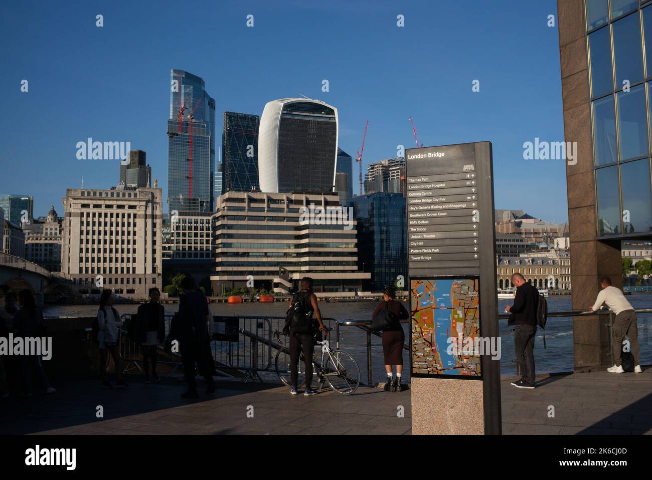 Una vista dal percorso del Tamigi vicino al London Bridge attraverso il Square Mile e il quartiere finanziario di Londra, guardando i grattacieli con la cartiera di direzione della mappa. Foto Stock