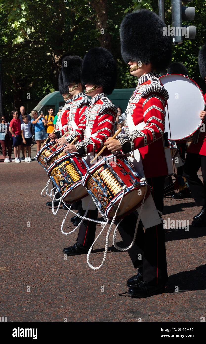 I batteristi delle guardie Coldstream marciano lungo la strada nel centro di Londra con i turisti che guardano Foto Stock