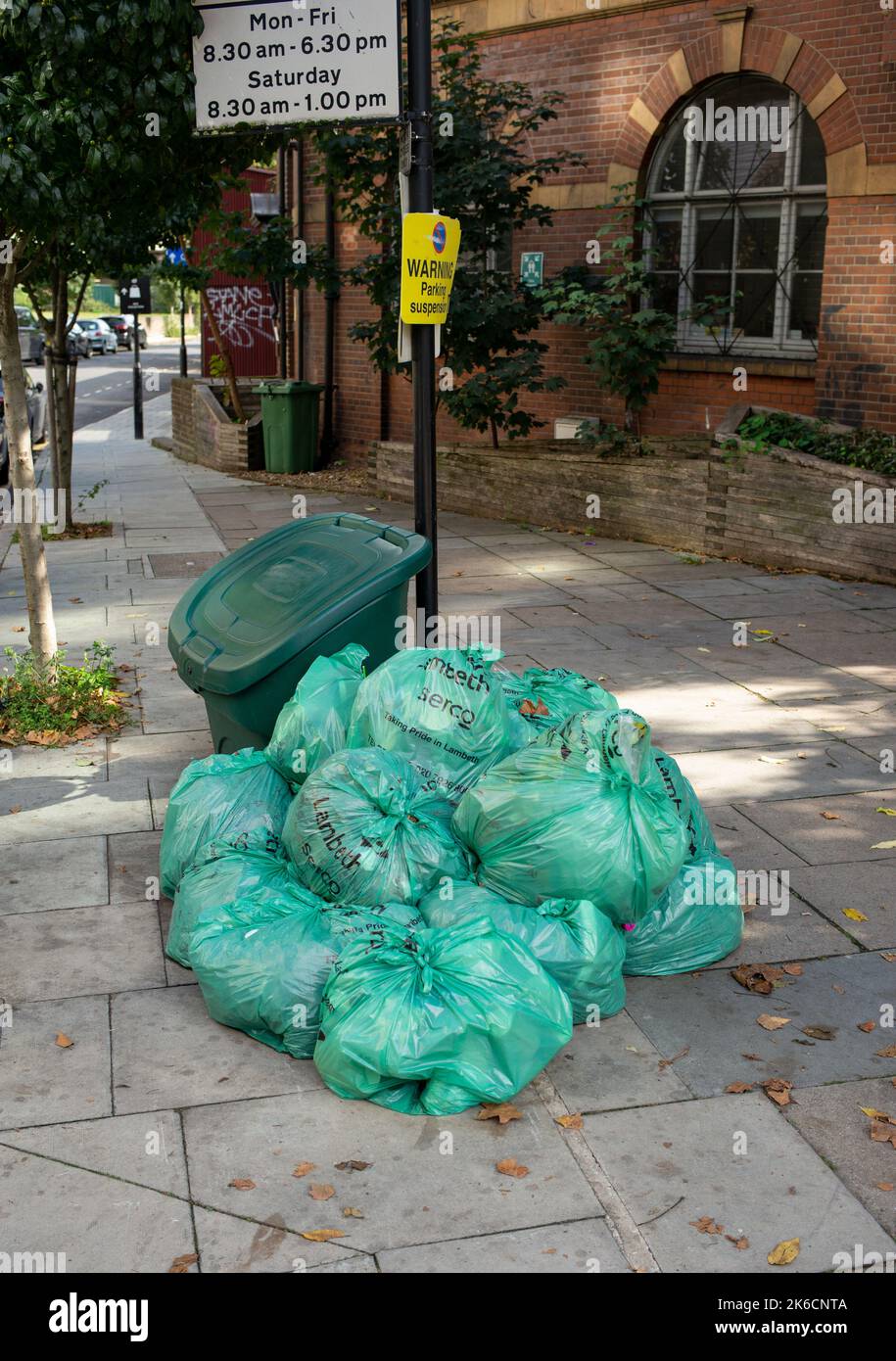 I sacchi verdi per la raccolta dei rifiuti Lambeth Council si sono accumulati per strada pronti per la raccolta a Londra UK. Foto Stock