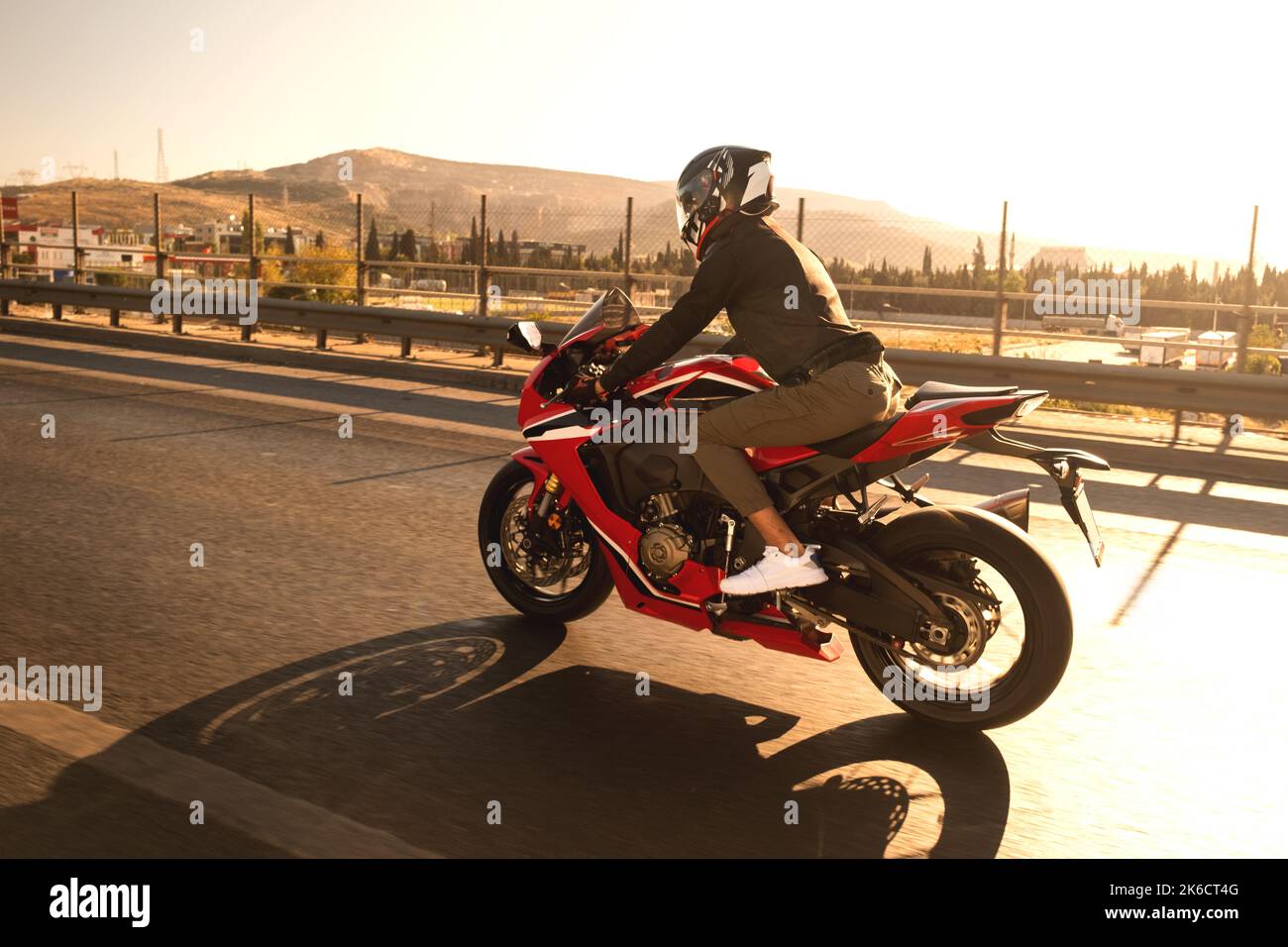 Vista laterale di un motociclista che guida una moto da corsa rossa sull'autostrada con sfocatura del movimento. Foto Stock