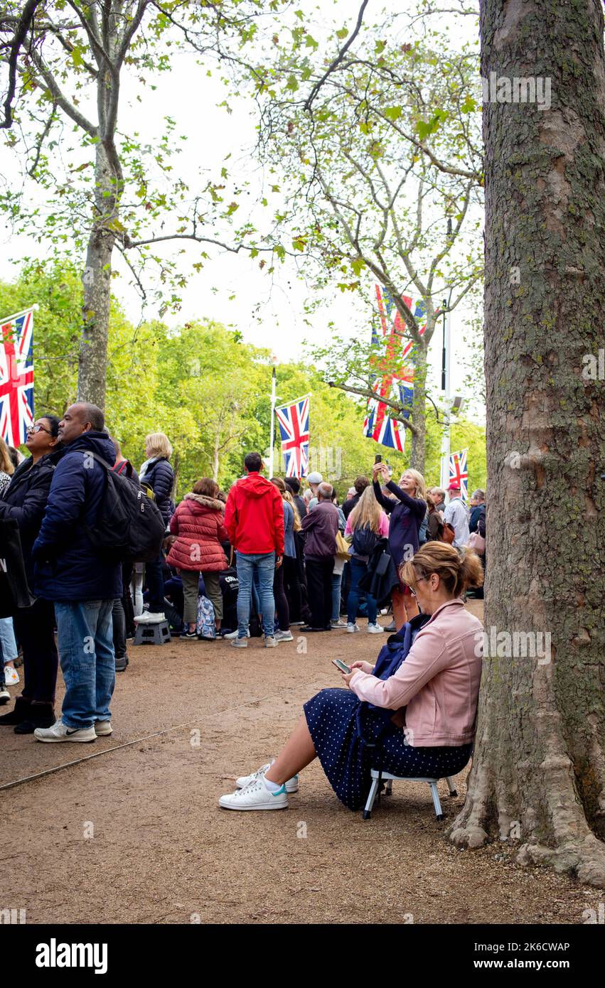 I membri del pubblico si siedono e aspettano sul Mall dopo aver assicurato il loro posto per assistere al Queens Coffin e al Royal Family Pass verso Windsor Hall. Foto Stock