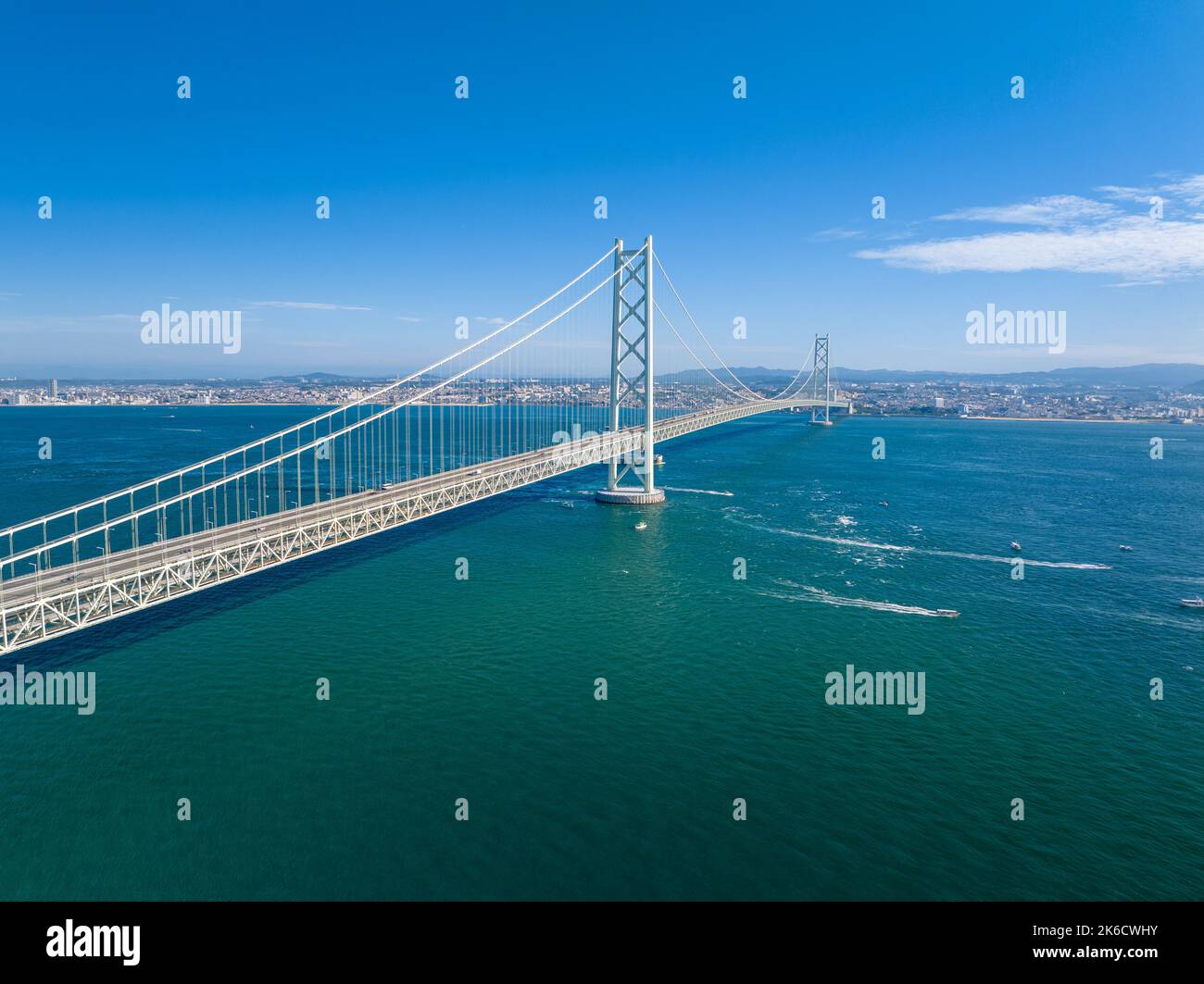 Piccole barche navigano sotto un lungo ponte sospeso nelle giornate di sole Foto Stock