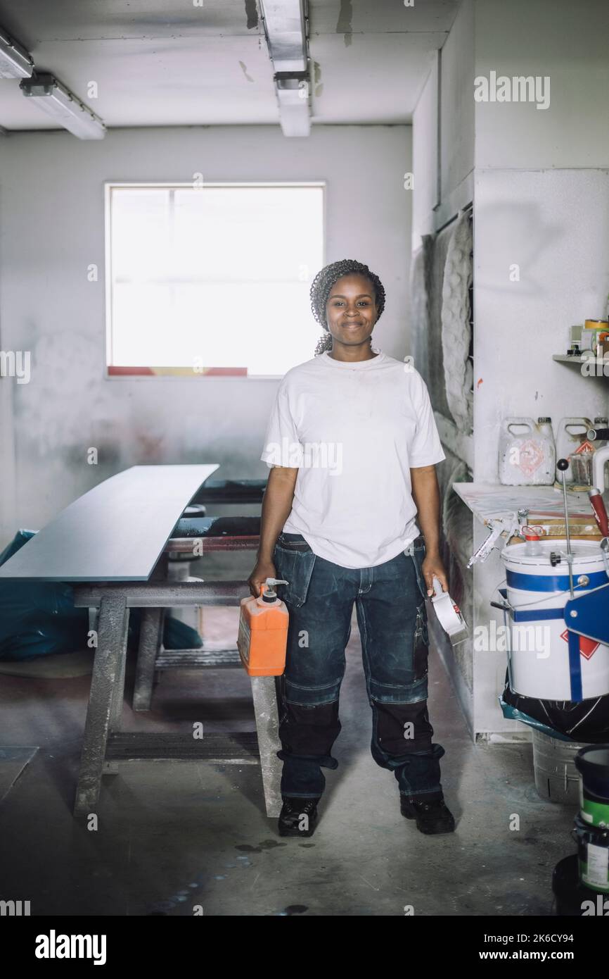 Ritratto a tutta lunghezza di una donna sorridente in piedi in officina Foto Stock