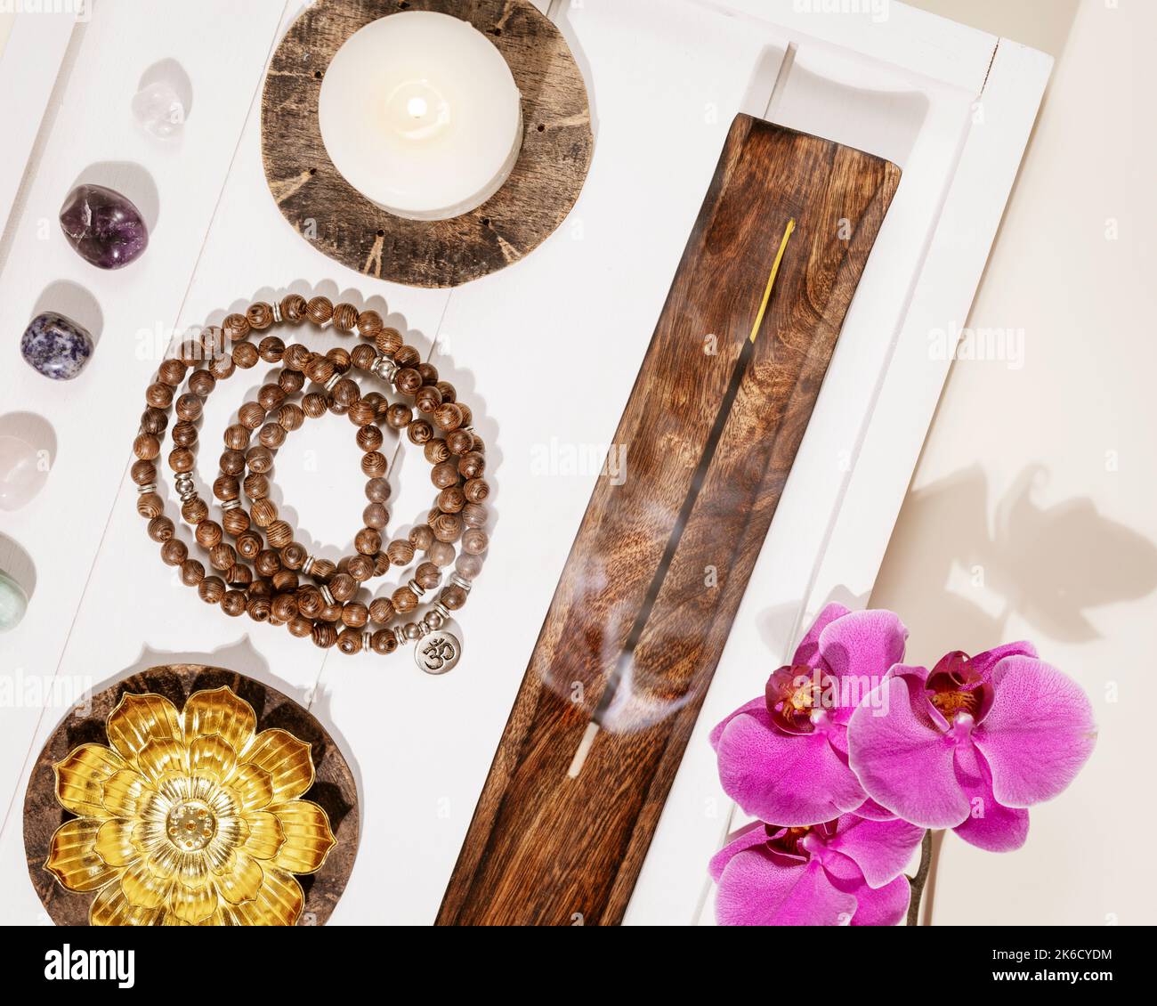 Perline di Rosario, candele, bastoncini aromatici, pietre di chakra e fiori di orchidea Foto Stock