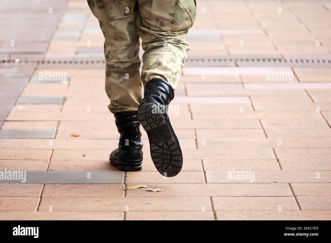Soldato in mimetizzazione militare e stivali camminando lungo la strada cittadina, gambe sul marciapiede. Concetto di servizio nell'esercito, mobilitazione Foto Stock