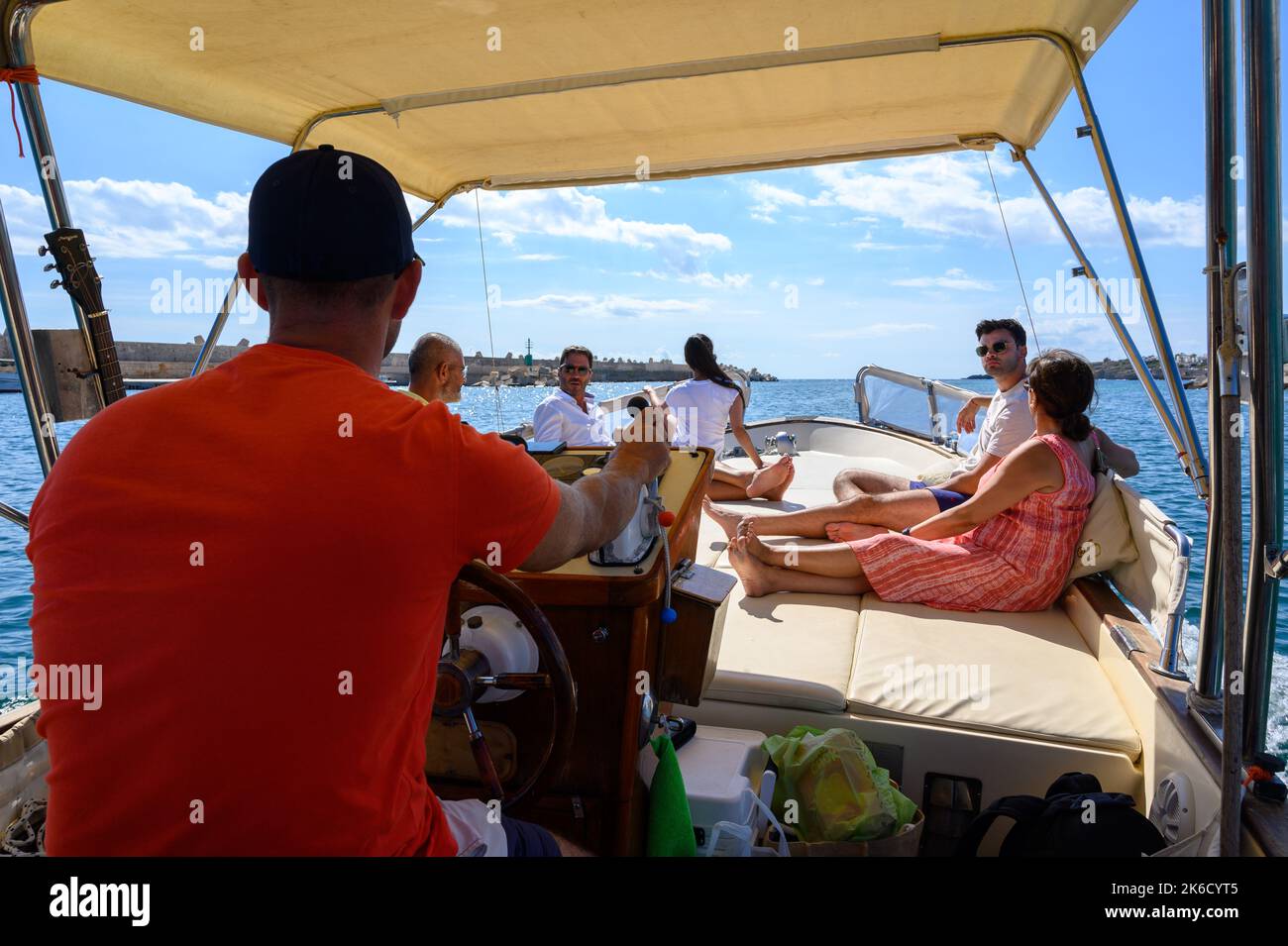 Una barca charter con turisti e equipaggio che parte dal porto di Santa Maria di Leuca per le grotte lungo la riva verso il mare Adriatico. Puglia, Italia. Foto Stock