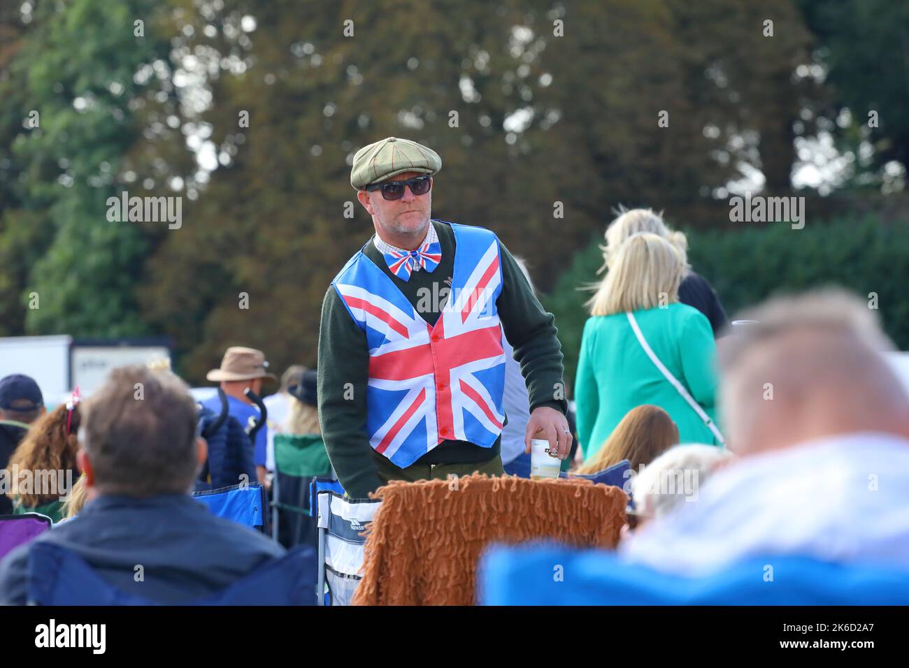 un uomo vestito con un cappotto in vita union jack e una cravatta ad arco dickie indossando anche occhiali da sole e un cappello piatto al wentworth woodhouse festival 2022 Foto Stock