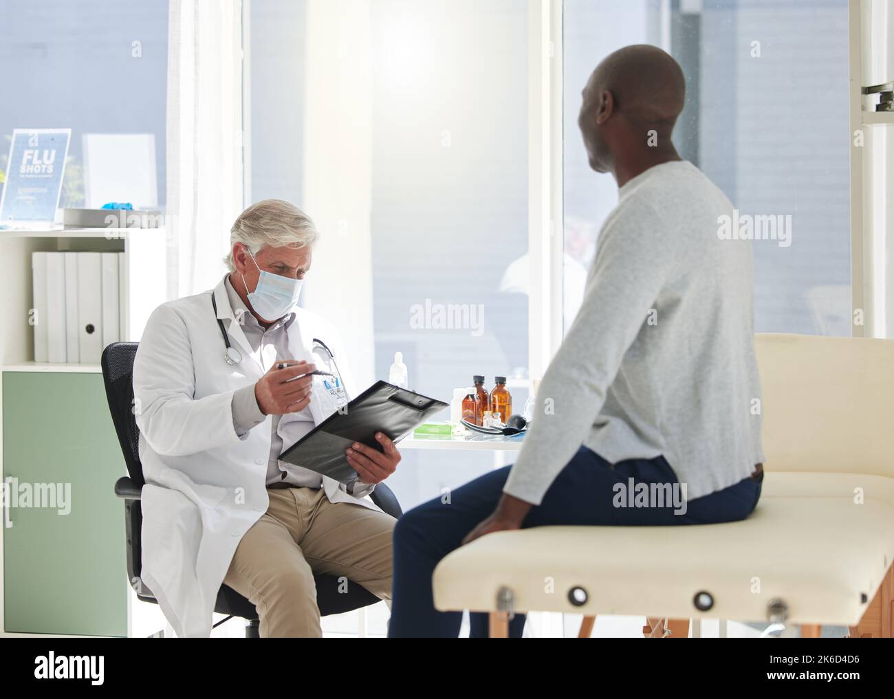 Un medico maturo che ha un controllo con un paziente in un ospedale. Foto Stock