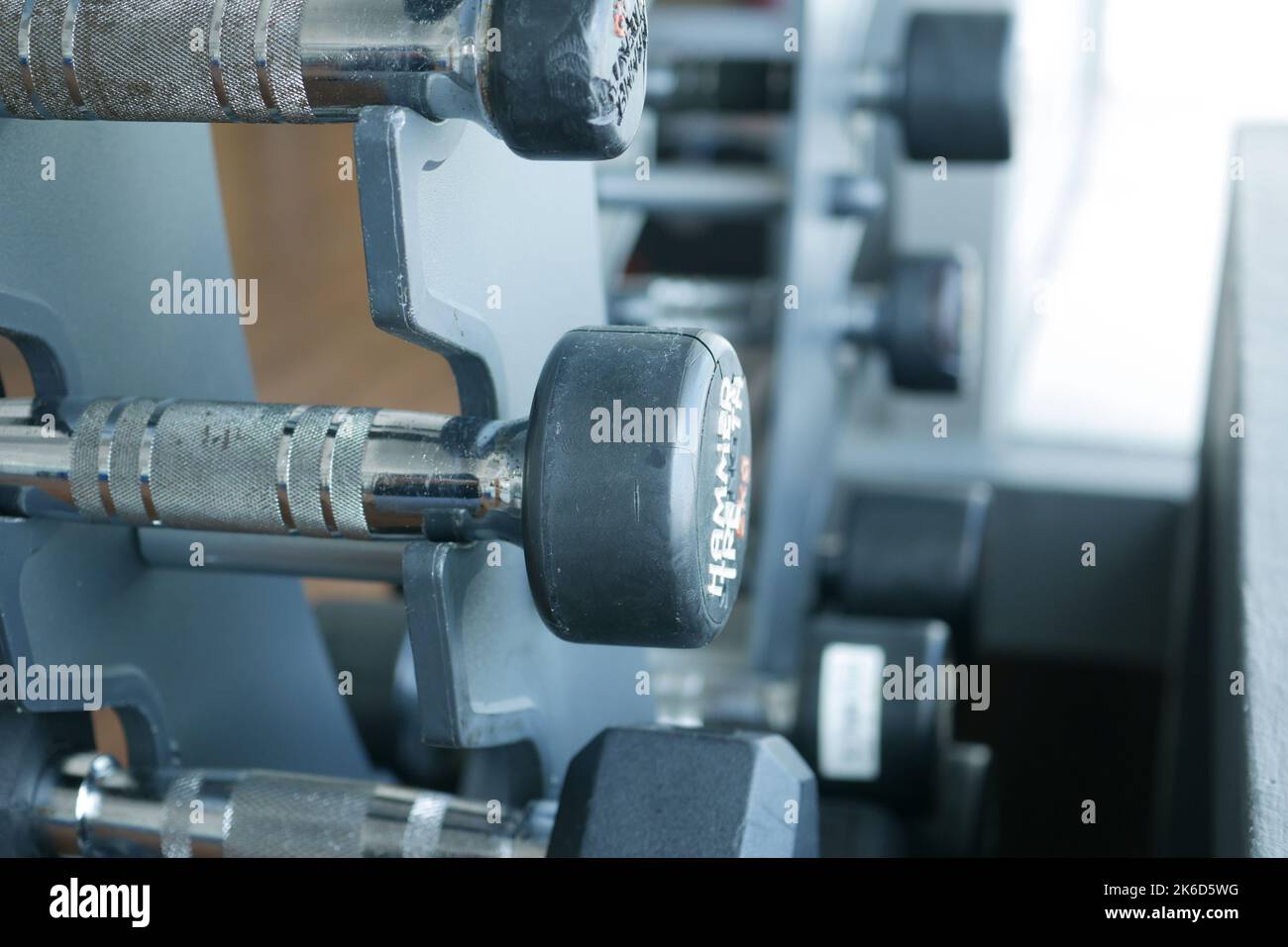 File di manubri di colore nero con numeri in palestra Foto Stock