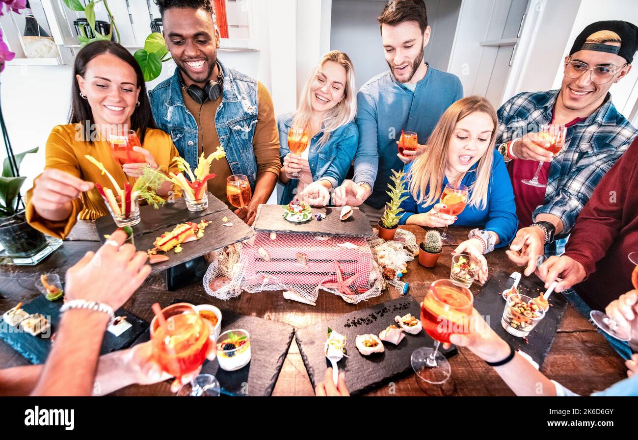 Gruppo di amici che si diverte a buffet prima di cena bevendo un cocktail spritz e mangiando degli spuntini - i giovani che si divertono insieme al lussuoso bar - S Foto Stock