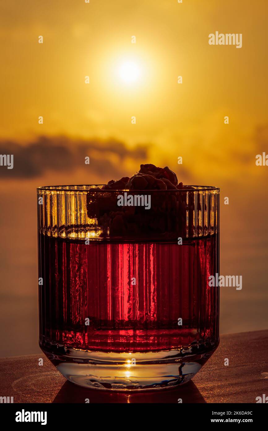 Classico cocktail Negroni bevanda alcolica in vetro retrò cristallo contro luminoso tramonto arancione. Foto Stock