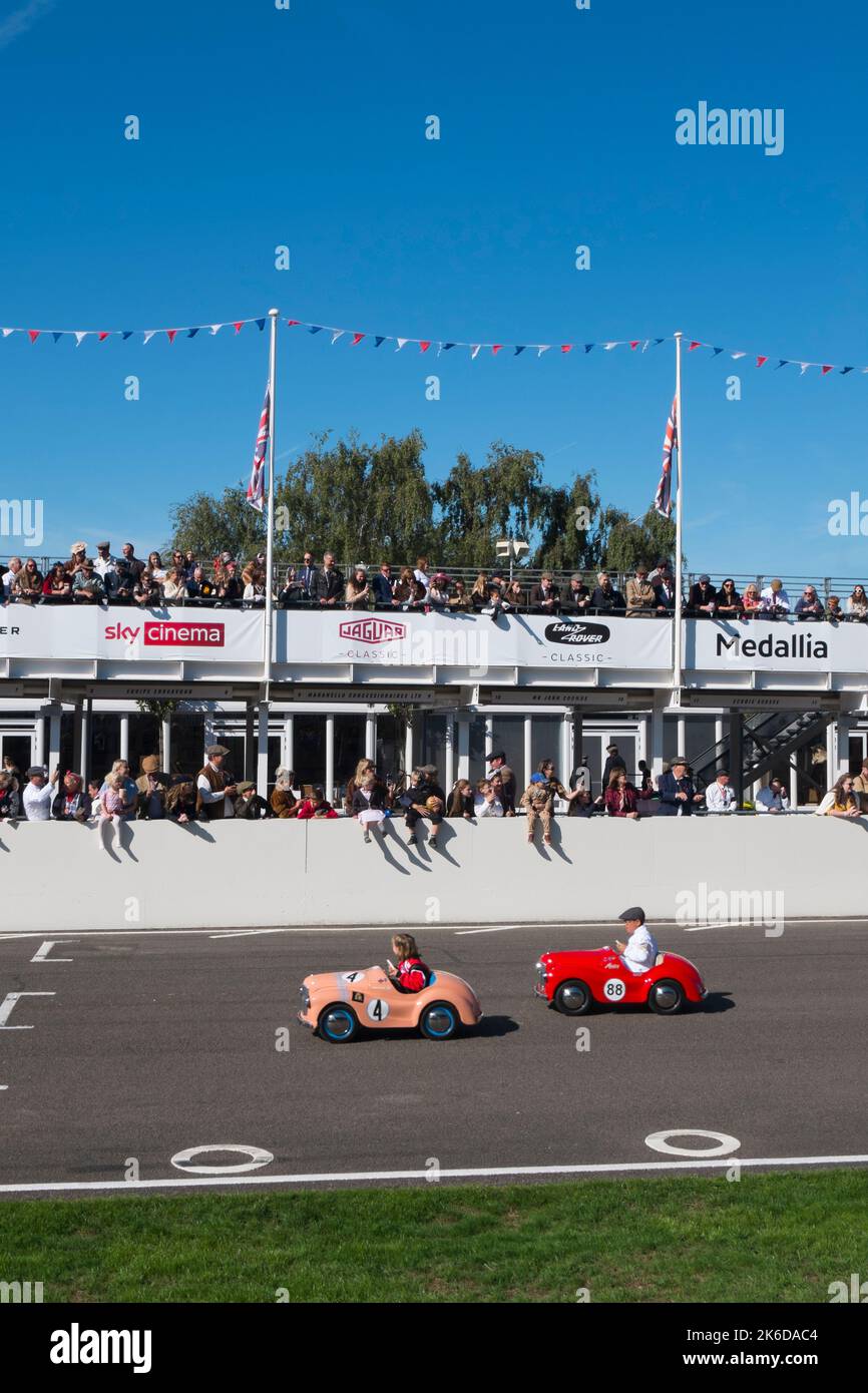 I bambini corrono con le loro auto a pedali Austin J40 sul rettilineo nella gara di Settrington Cup, Revival Meeting, circuito automobilistico di Goodwood, Goodwood, Regno Unito Foto Stock