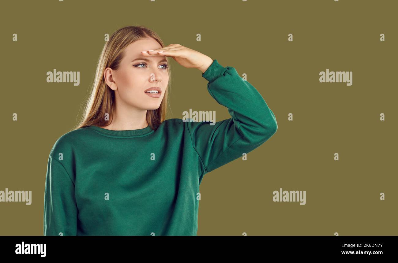 Donna che in previsione di qualcosa tiene la mano sopra gli occhi e guarda in lontananza. Foto Stock