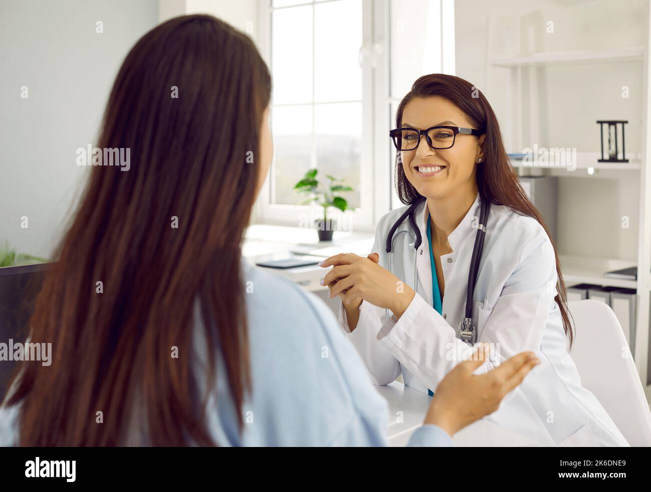 Medico felice sorridendo mentre ascolta il paziente durante la consultazione medica in clinica Foto Stock