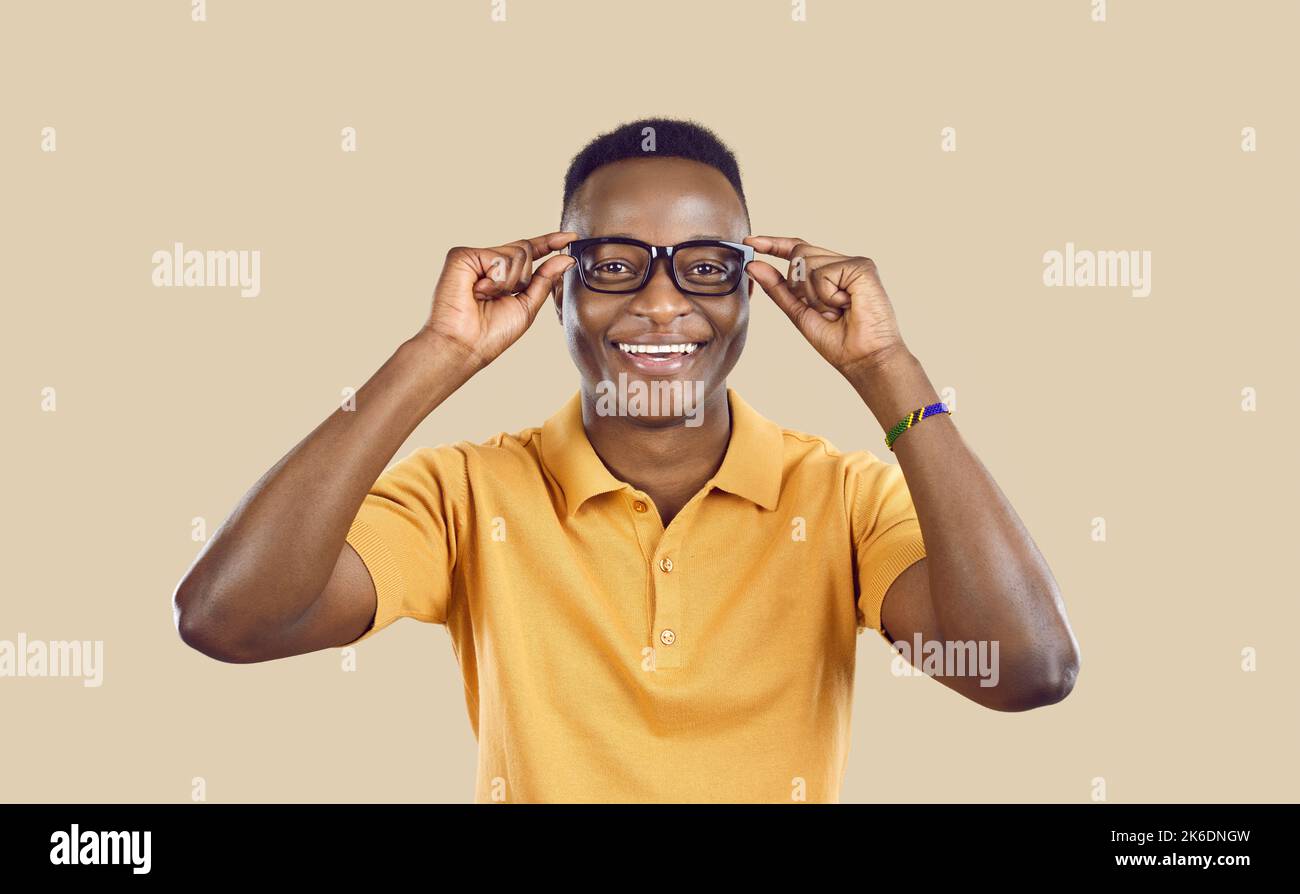 Studio ritratto di felice giovane uomo africano mettere gli occhiali e sorridere Foto Stock