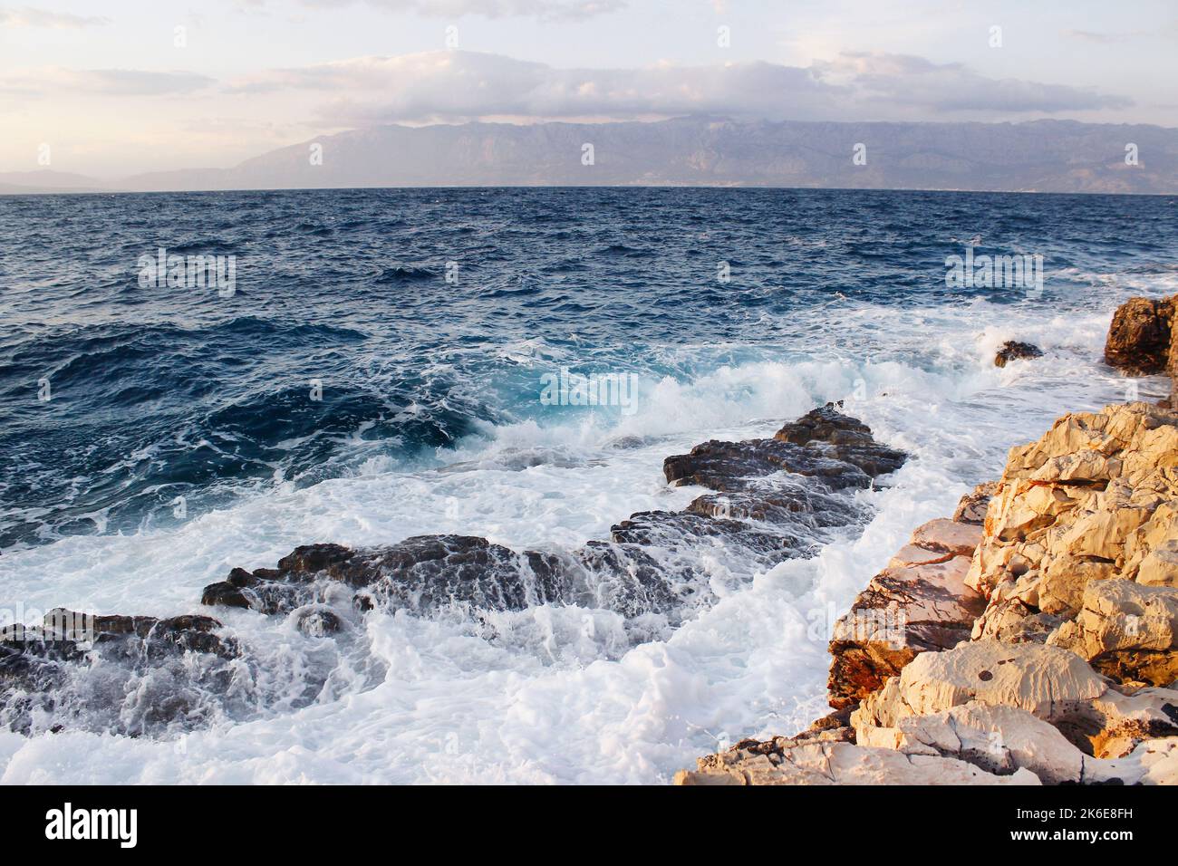 Onde di mare che colpiscono la spiaggia rocciosa Foto Stock