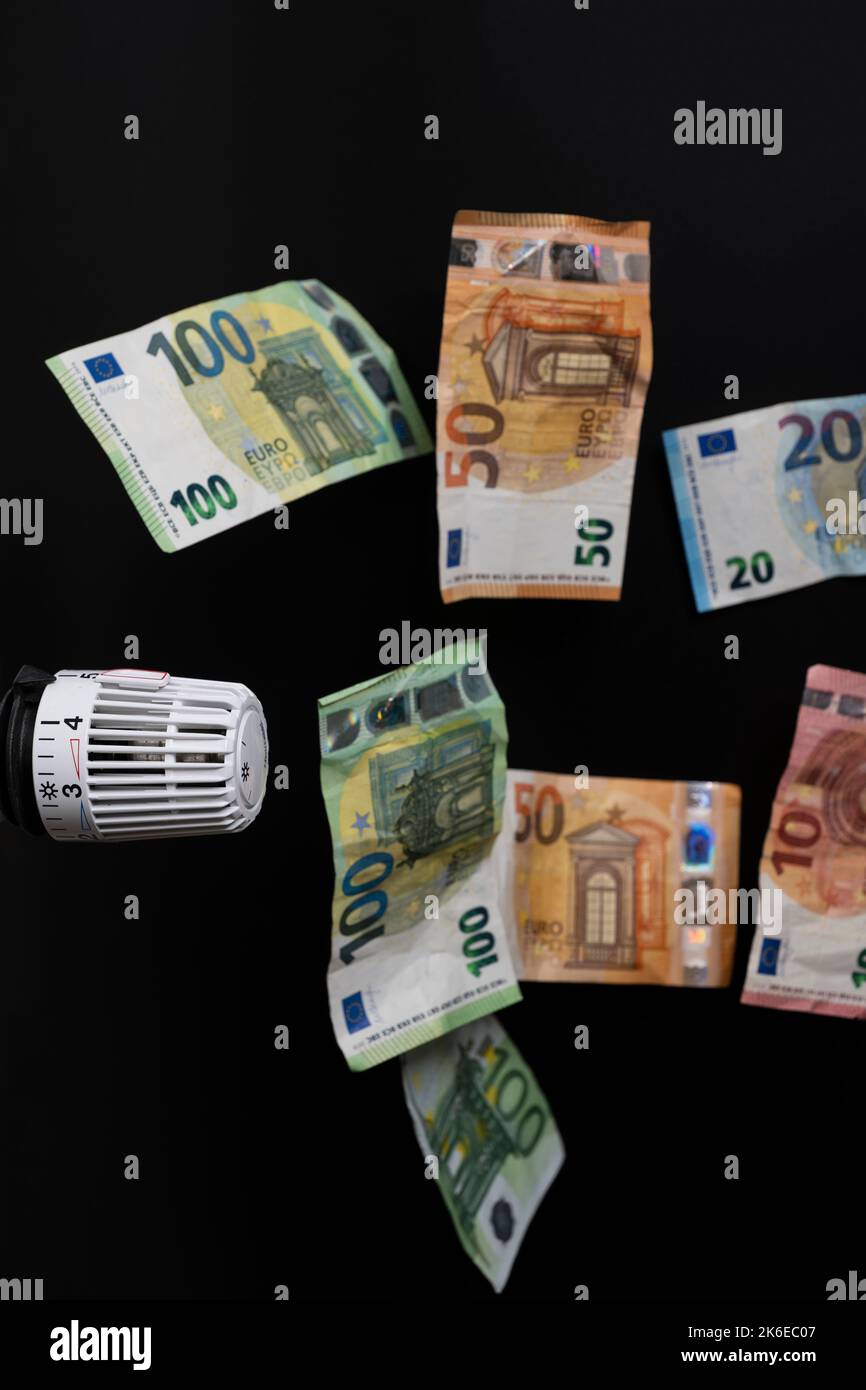 costi di riscaldamento costosi. Termostato con diverse banconote in euro in caduta Foto Stock