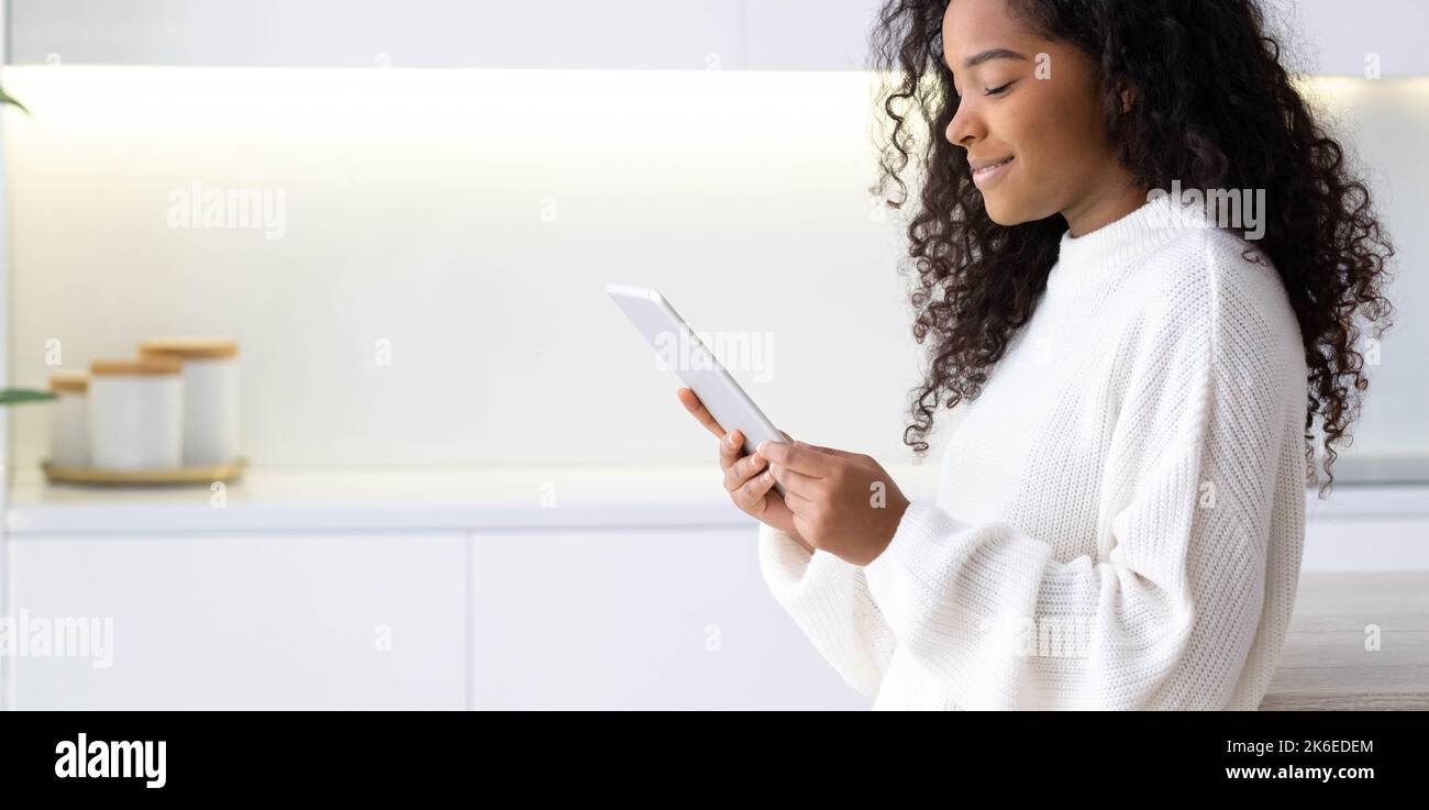 Banner African American Girl utilizzando iPad tablet a casa premendo il dito, leggendo i social media Internet, digitando testo o shopping online. Freelance Foto Stock