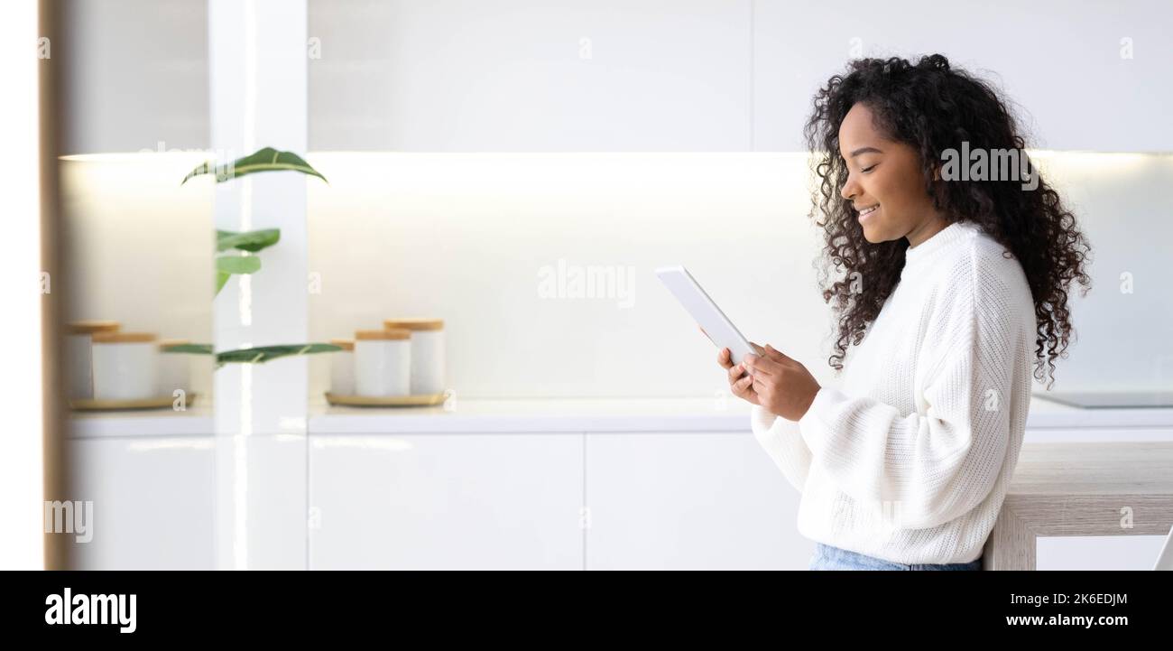 Banner African American Girl utilizzando iPad tablet a casa premendo il dito, leggendo i social media Internet, digitando testo o shopping online. Freelance Foto Stock