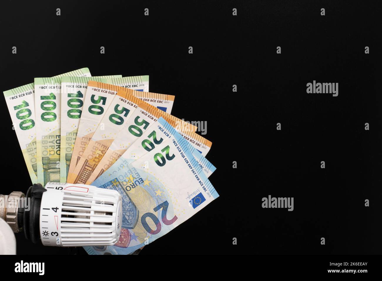 Termostato di riscaldamento con vano in banconote in euro sullo sfondo Foto Stock