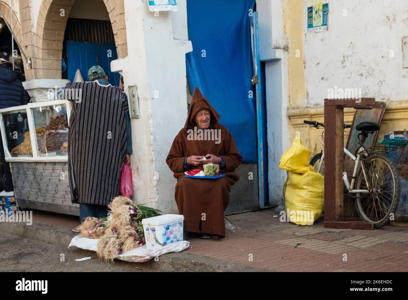 Due uomini marocchini in abbigliamento tradizionale che vendono e comprano cibo nella storica medina della città vecchia, Essaouira, Nord Africa Foto Stock