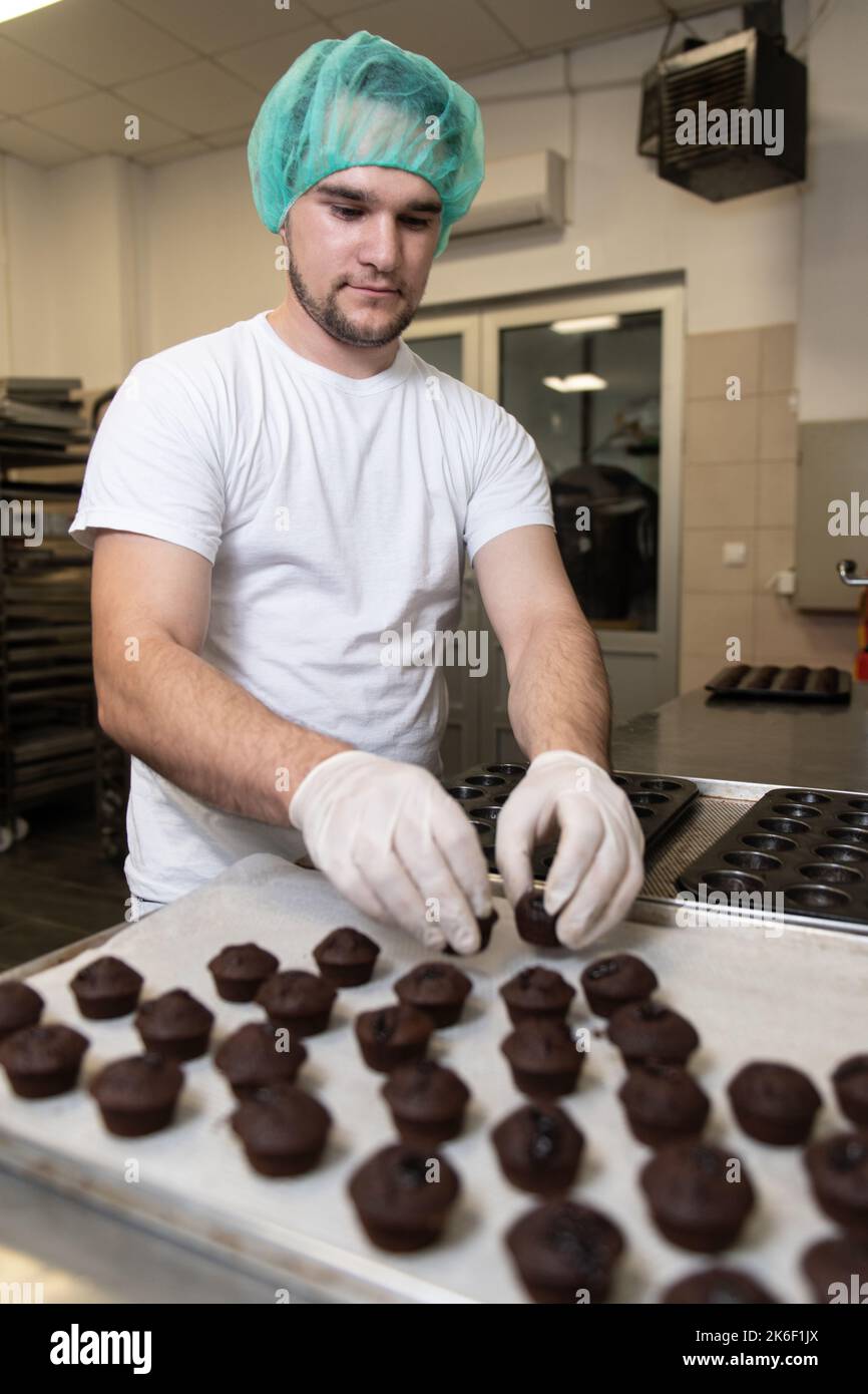 Chef maschile preparare o decorare i muffin al cioccolato Cupcake Foto Stock