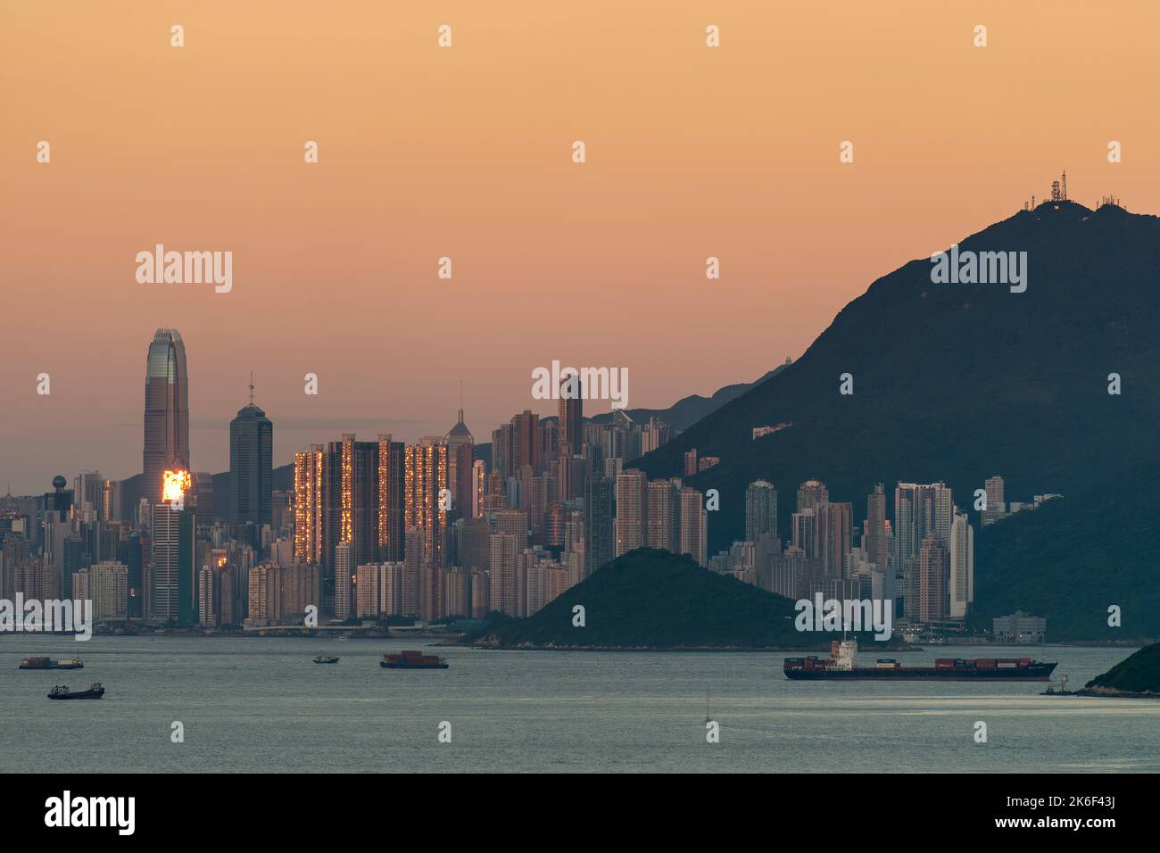 Il sole tramontato si riflette negli alti edifici dell'Isola di Hong Kong, visti contro il cielo arancione del fenomeno Belt of Venere Foto Stock
