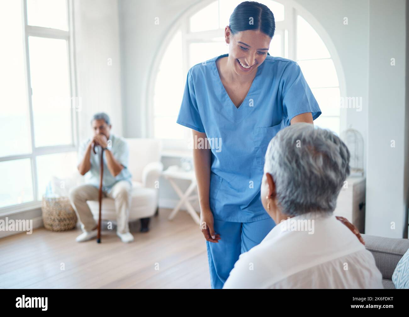 Come stai facendo oggi. una giovane allettante infermiera che fa le sue rotonde nella casa di vecchiaia. Foto Stock