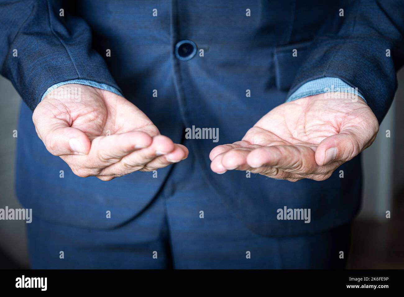 Uomo d'affari senza testa che tiene qualcosa senza tema. Un uomo mendicante in una giacca mendica. Il concetto di scelta. Foto Stock