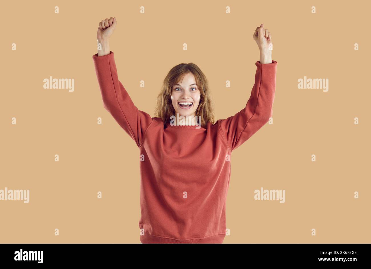Felice donna eccitata che celebra la vittoria, alzando le mani, sorridendo e allietando Foto Stock