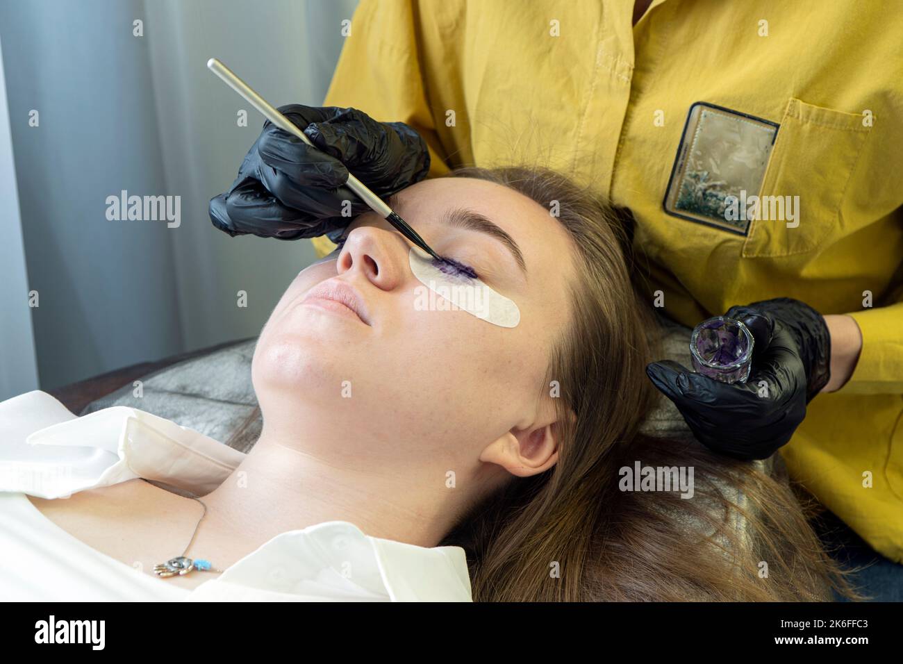 Donna sulla procedura cosmetica al salone. Una ragazza in un salone di bellezza sulla procedura di colorare le sue ciglia. Cura per sopracciglia e ciglia. Foto Stock