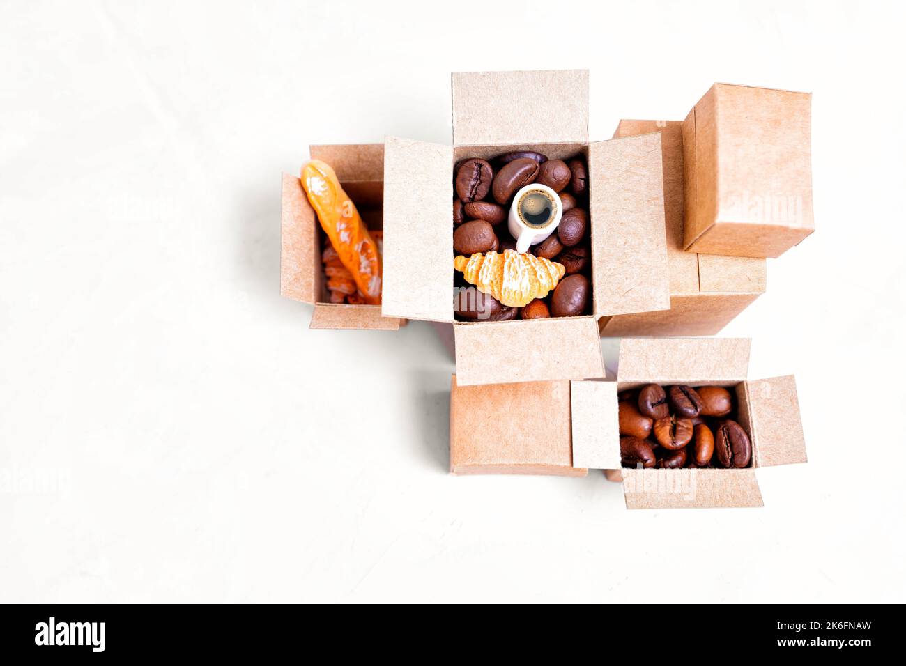 Concetto di forniture Creative Coffee Shop: Scatole di cartone in miniatura piene di chicchi di caffè torrefatti e prodotti da forno. Foto Stock